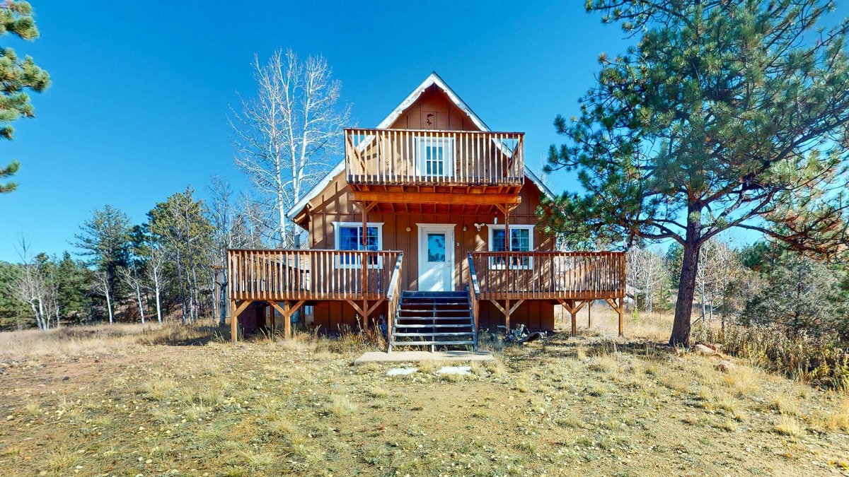 Florissant House | A-frame home lined by trees with wood stove, balcony, children's items, & W/D
