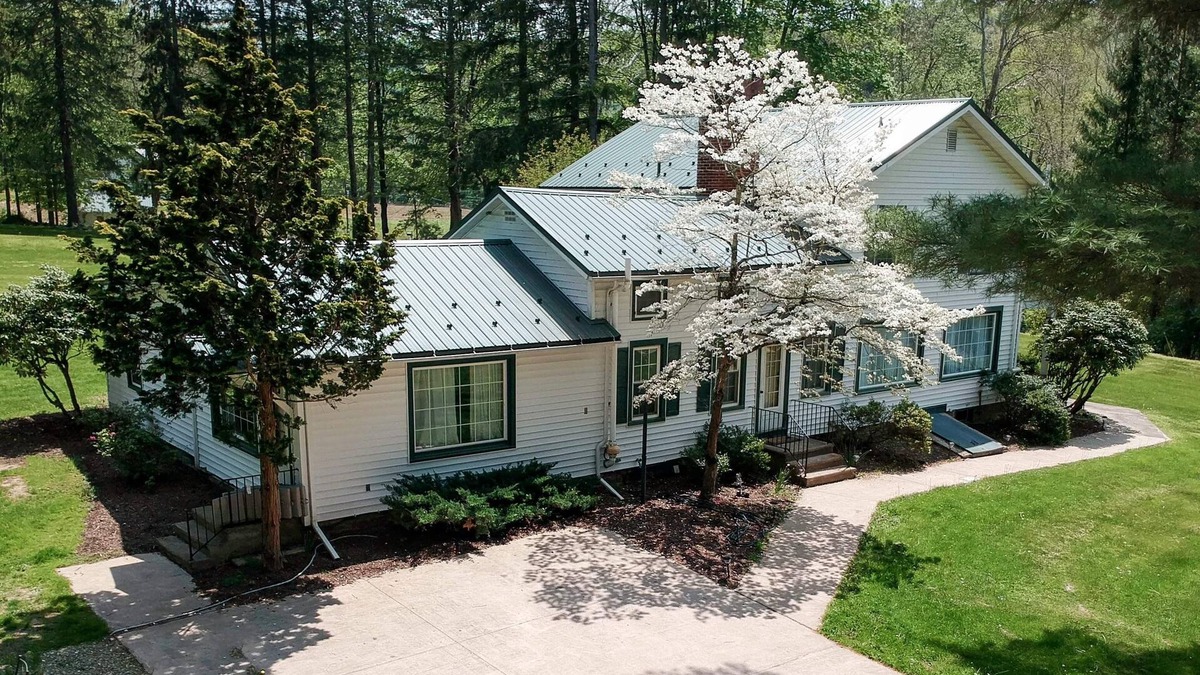 Hillsgrove House | Creek side house with fireplace and concrete driveway.