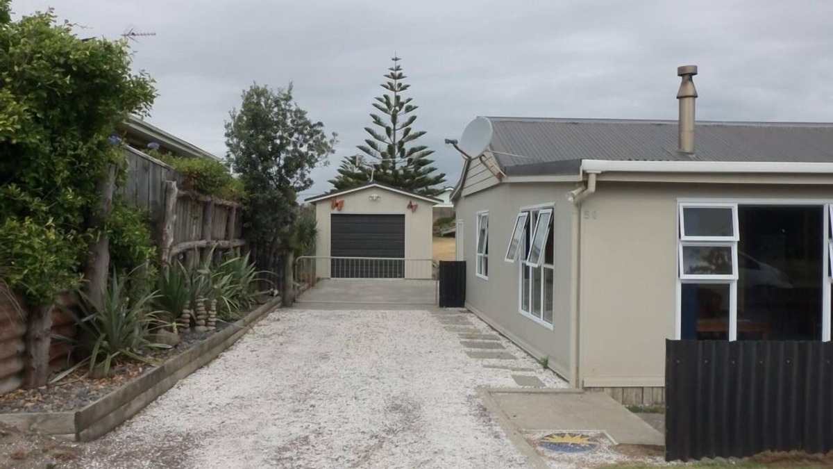 Waitarere Beach House | HAPPY HAVEN has Kiwi Bach character with location.