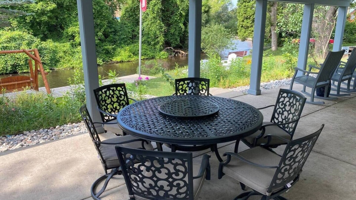 Grayling House | Riverfront Escape in Downtown Relax on the Covered Patio with the Family