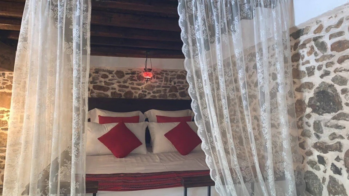 Asklipiio House | Traditional stone built single room house with traditional bed.