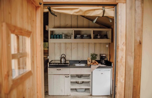 Lieren House | Luxury glamping in the Veluwe: Safaritent for 6 guests with private bathroom, full kitchen, made-up beds & playground view veranda.
