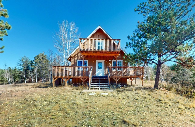 A-frame home lined by trees with wood stove, balcony, children's items, & W/D
