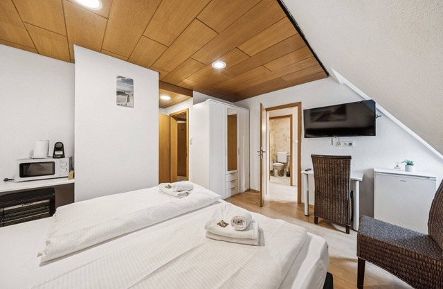 Comfortable room with a double and single bed, private bathroom, flat-screen TV, fridge, microwave, coffee machine, and cozy seating area. Ideal for small families or friends traveling together.