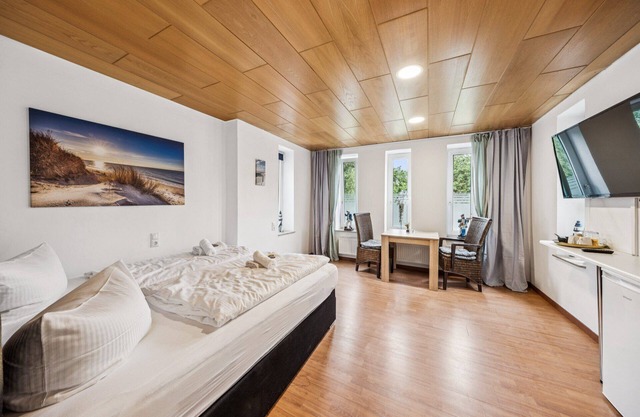 Cozy double room, seating area, flat-screen TV, and modern bathroom with shower. Ideal for couples and short stays – enjoy a relaxed atmosphere with warm wood accents and coastal charm.
