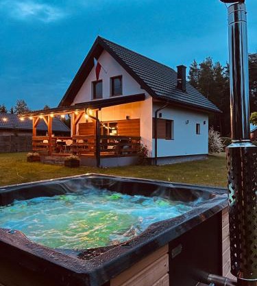 Domek z kominkiem nad jeziorem z jacuzzi ogrodowym