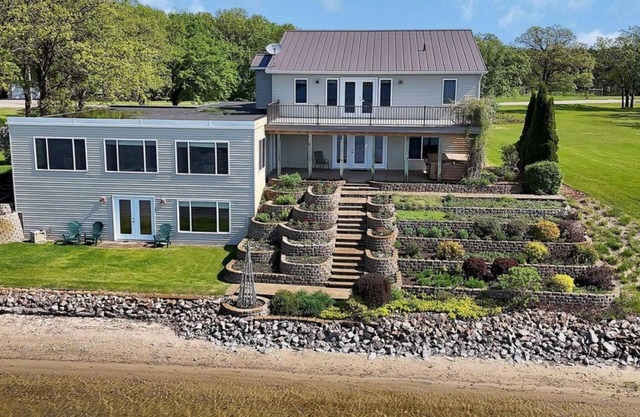 Gather at this spacious 5-bedroom lake home with 277' sandy beach, private dock